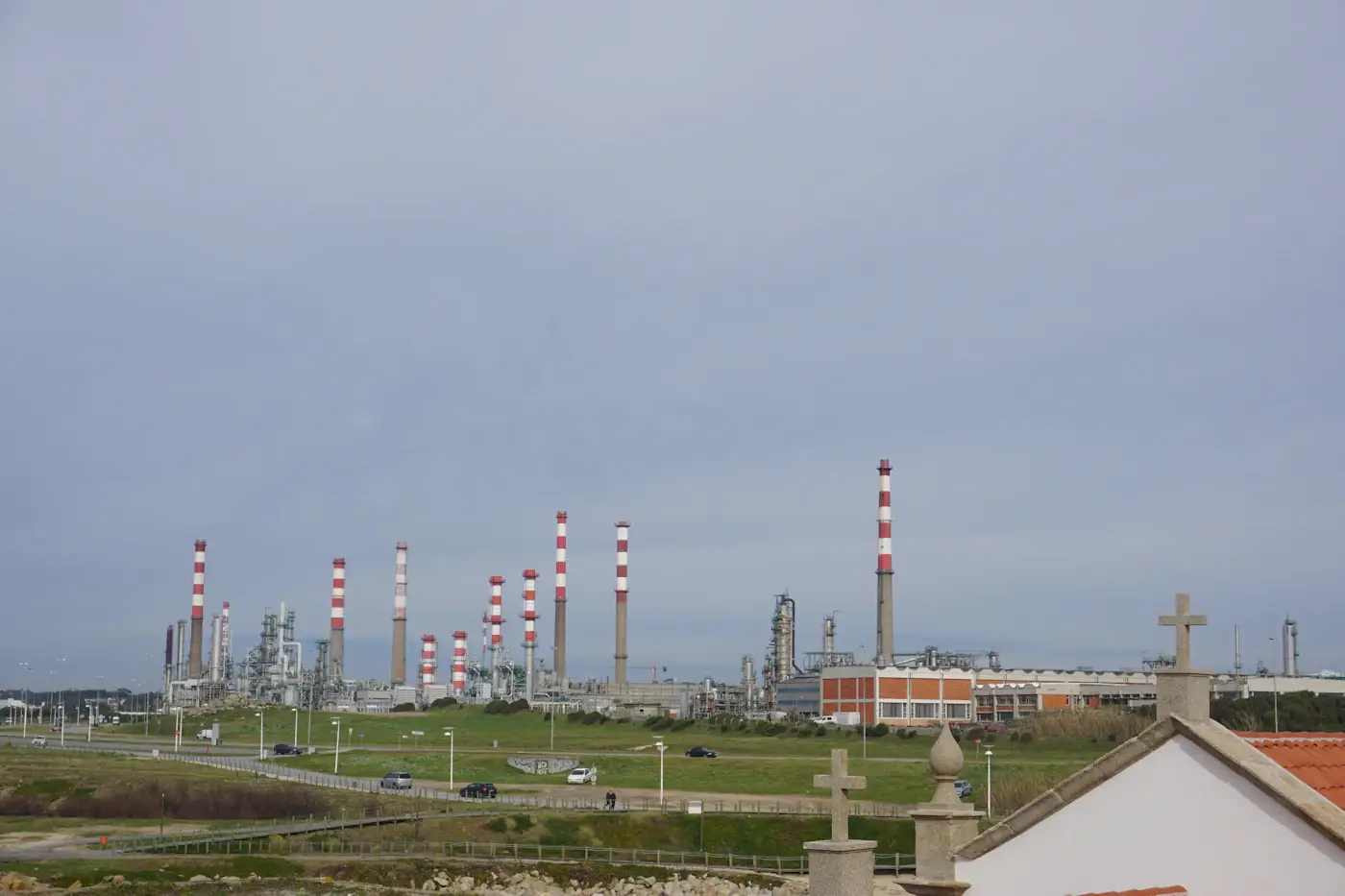 Oil refinery with red and white striped stacks beside open fields